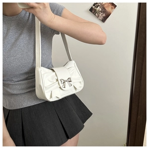 Gros plan d'un sac sous les bras en cuir plissé blanc avec boucle de nœud argentée