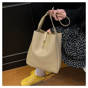 Detail view of the beige bucket bag with its elegant golden metal buckle and smooth leather