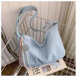 Detail of light blue-grey crescent tote bag with tennis racket pendant in a metal basket