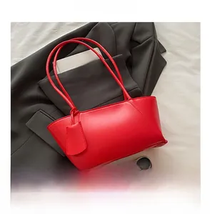 Détail du sac à épaule en cuir rouge brillant avec fines bretelles et étiquette latérale
