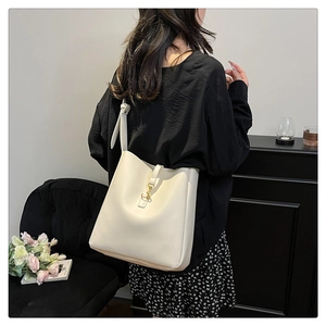 Detail of soft cream white bucket bag featuring a polished gold metallic buckle closure