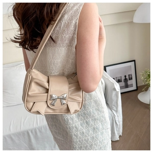 Detailed view of beige leather shoulder bag with a large 3D bow and silver buckle