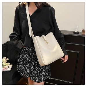 Detail of a creamy white leather bucket bag with gold hardware and wide adjustable strap