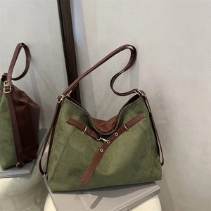 Olive green and brown suede patchwork tote bag on a book in an aesthetic indoor setting