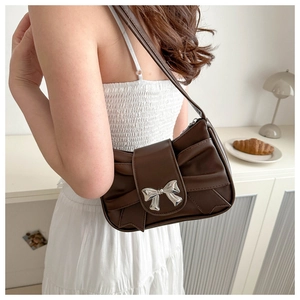 Detail of dark chocolate leather underarm bag featuring a pleated bow and silver buckle