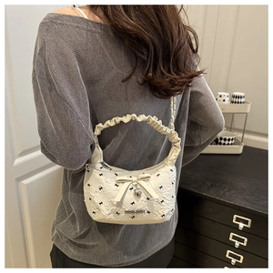 Detail of white pleated handle bag with black bow embroidery and heart pendant