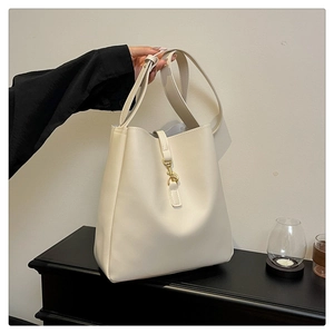 Close-up of cream-white bucket bag with smooth leather texture and gold metal buckle