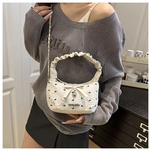 Detail of white textured handbag with satin bow, heart pendant and cloud ruched handle