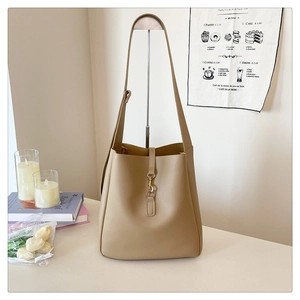 Minimalist camel bucket bag with metal buckle hanging in a modern lifestyle setting