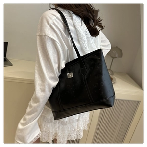 Detailed side view of a large black embossed leather tote bag with silver buckle