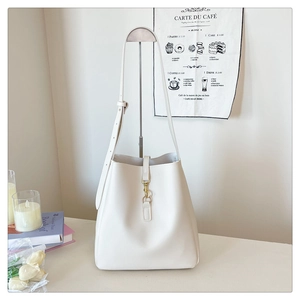 Close-up of ivory white bucket bag with gold metal clasp and vertical stitching detail