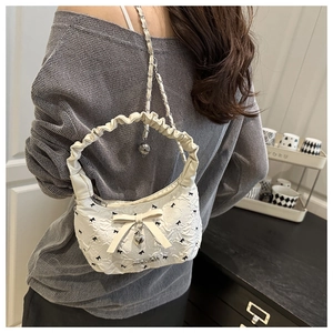 Detail of white half-moon bag with jacquard texture and silver heart pendant