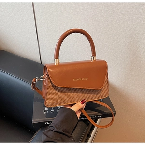 Detail of vintage brown leather and woven texture handbag on a book in urban setting