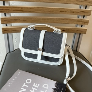 Gray and white minimalist canvas crossbody handbag with top handle on a wooden chair