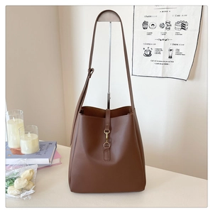 Detailed view of brown leather bucket bag with gold metal buckle clasp and slim strap