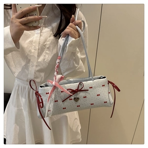 Détail du sac bleu à nœuds rouges avec pendentif cœur et bandoulière en dentelle