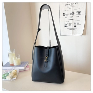 Detailed view of black bucket bag featuring a sleek golden metal clasp closure