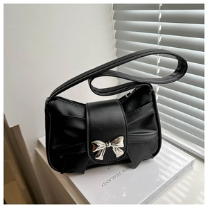 Detail of black pleated bow shoulder bag with silver metal clasp on minimalist background