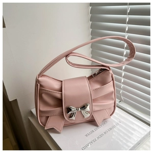 Detail of pink pleated leather bag featuring a decorative bow and metallic centerpiece