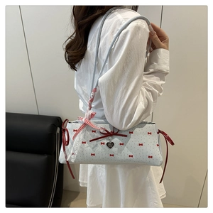 Sac seau bleu clair avec nœuds rouges et pendentif cœur porté par le mannequin