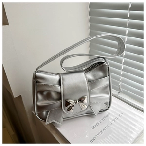 Detail of silver metallic bag featuring a large bow and butterfly metal buckle clasp