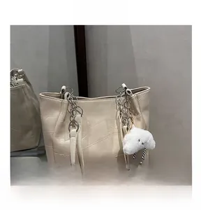 Detail showing beige tote bag with metallic chain strap and white plush cloud charm
