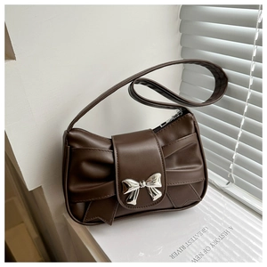 Detail of matte brown leather shoulder bag featuring a unique bow-shaped fold and silver buckle