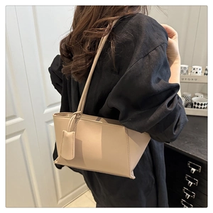 Détail du sac à bandoulière minimaliste en similicuir beige sur un haut noir
