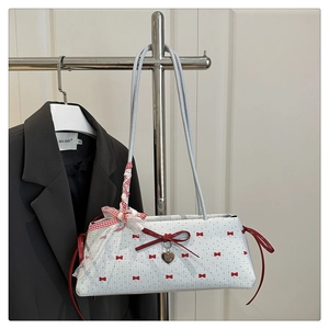 Détail du sac bleu clair avec imprimé nœud rouge et pendentif en forme de cœur argenté