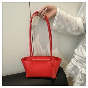 Detail of red leather trapezoid handbag with dual shoulder straps and matching hangtag