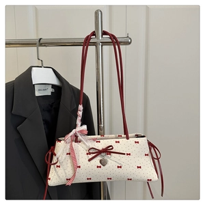 Détail du sac blanc à motifs de nœuds rouges et pendentif cœur sur support métallique