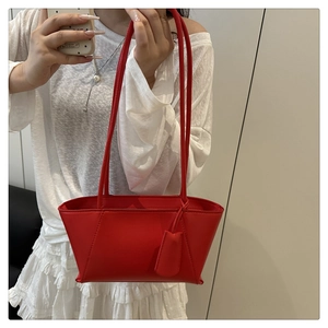Vue détaillée du sac à main rouge en cuir avec coutures en V et pendentif assorti