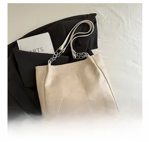 Detail of beige tote bag with geometric texture and silver chain strap on professional setting