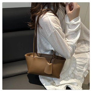 Detailed view of deep brown leather tote bag texture and hanging leather tag accessory