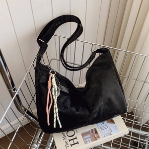 Minimalist black suede tote bag with woven charm and silver abacus on art books