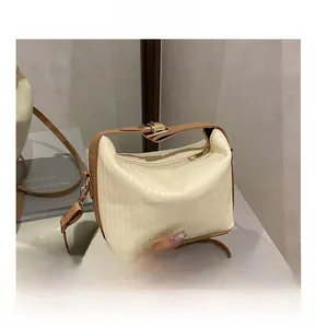 Detail view of cream shoulder bag with vertical texture and adjustable brown strap