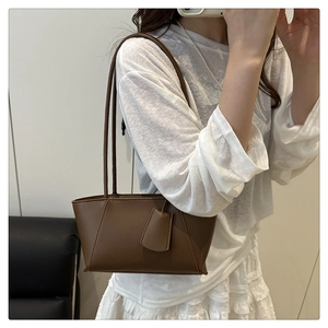 Détail d'un sac cabas minimaliste en cuir marron avec de fines bandoulières quotidiennes