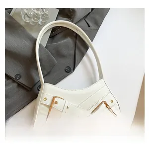 Close-up of white crocodile pattern shoulder bag featuring decorative gold buckle straps