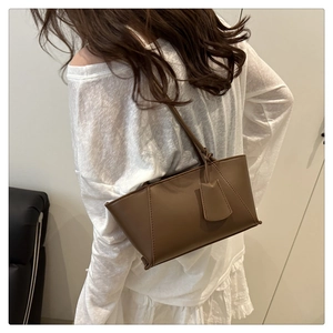 Brown leather handbag shown on model for size perspective and elegant urban style