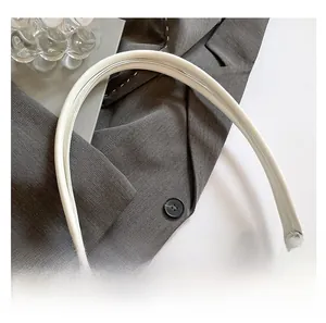 Detail of white crocodile embossed texture on a stylish underarm bag with long handle