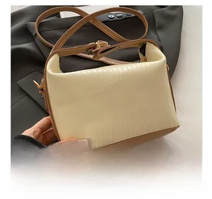Detail of beige pleated fabric texture and adjustable brown shoulder strap of the handbag