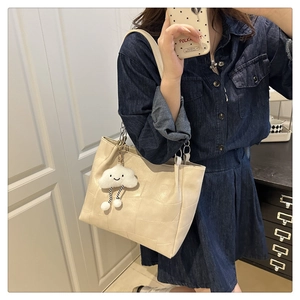 Close-up of beige quilted checkerboard tote bag with cute cloud charm on shoulder
