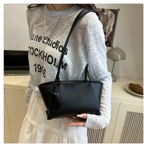 Close-up of a black minimalist faux leather tote bag with a matching rectangle tag