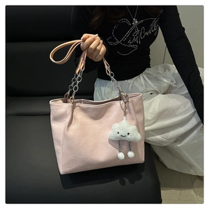 Detail of pink geometric embossed tote bag with metal chain strap and cloud charm