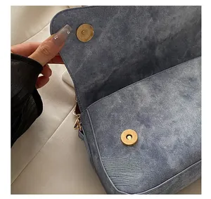 Detailed close-up of a blue denim textured bag featuring a matte gold magnetic snap buckle