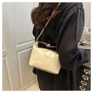 Detail of minimalist pleated cream shoulder bag with brown leather strap on model