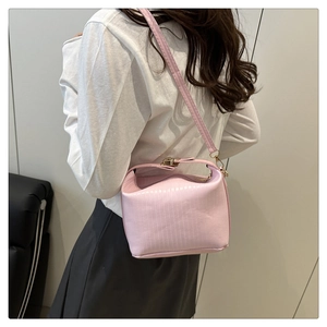 Detail of pink pleated crossbody bag with metal clasp worn by model for size reference