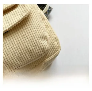 Macro detail of high-quality light beige corduroy fabric texture on a trendy crossbody bag