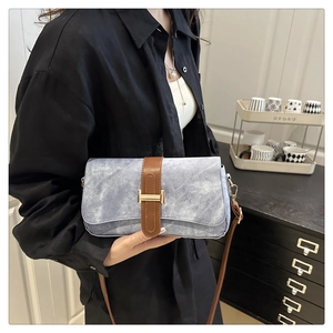Detail of light blue textured crossbody bag with gold H clasp and brown strap