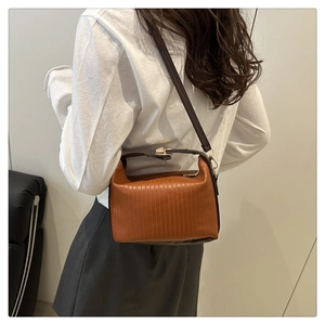 Detail showing caramel brown pleated faux leather texture and golden metal buckle on handbag